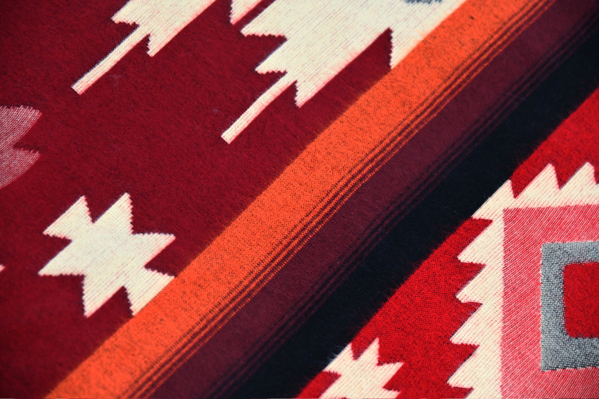 Close-up of the red, ivory and orange geometric pattern and woven alpaca texture