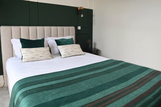 Emerald Forest striped alpaca wool blanket spread across a bed