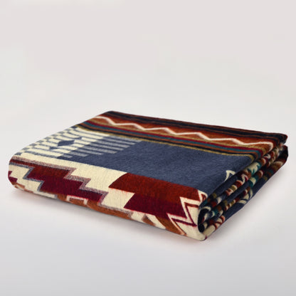 Folded Andean Horizon Aztec alpaca blanket in blue, burgundy, rust and ivory on a light background