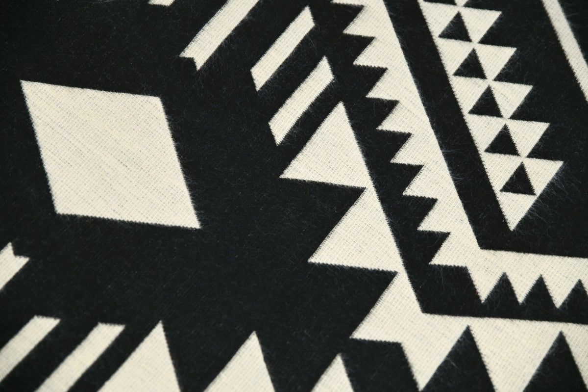 Close-up van het krachtige zwart-beige geometrische patroon en de geweven alpacatextuur
