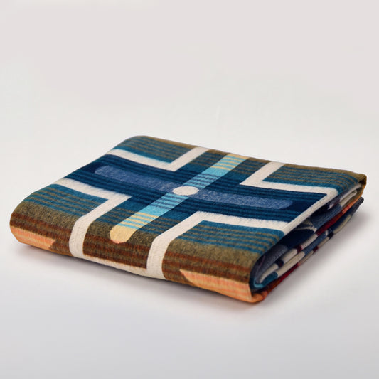 Folded Aztec Meridian reversible alpaca blanket in blue, turquoise, ivory and orange