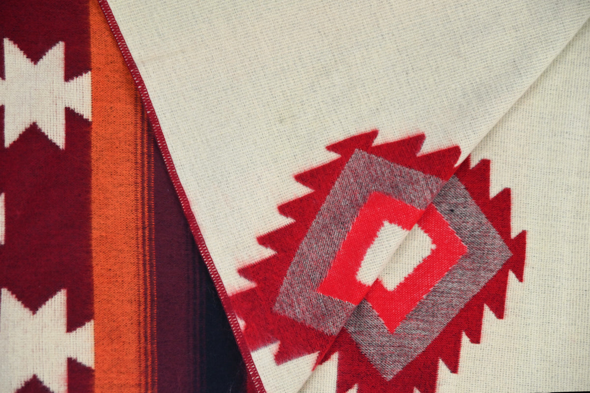 Reversible ivory side of the Aztec Red alpaca blanket with a folded patterned corner