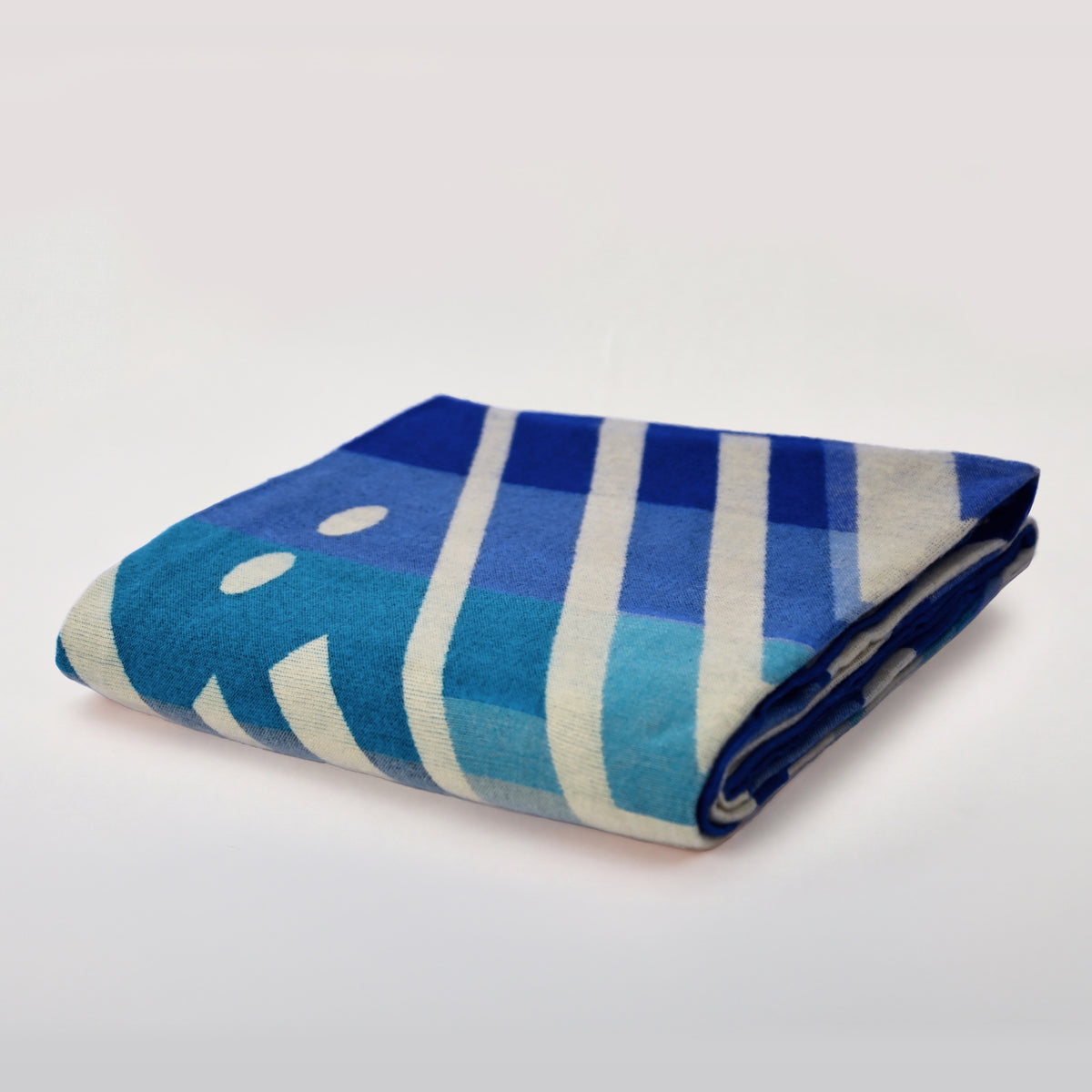 Folded Aztec Blue Geometric alpaca blanket in blue, turquoise and ivory on a light background