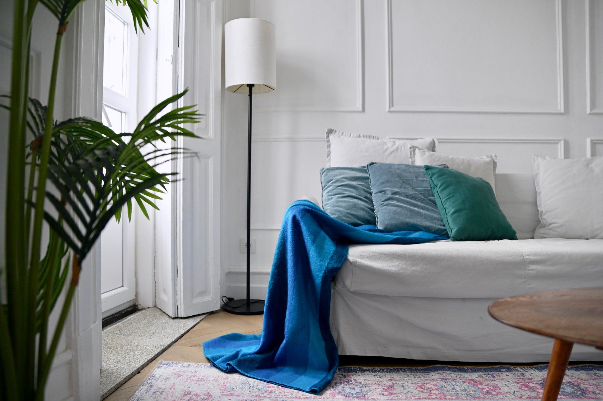 Living room with a gray sofa, blue alpaca blanket, and green cushions.