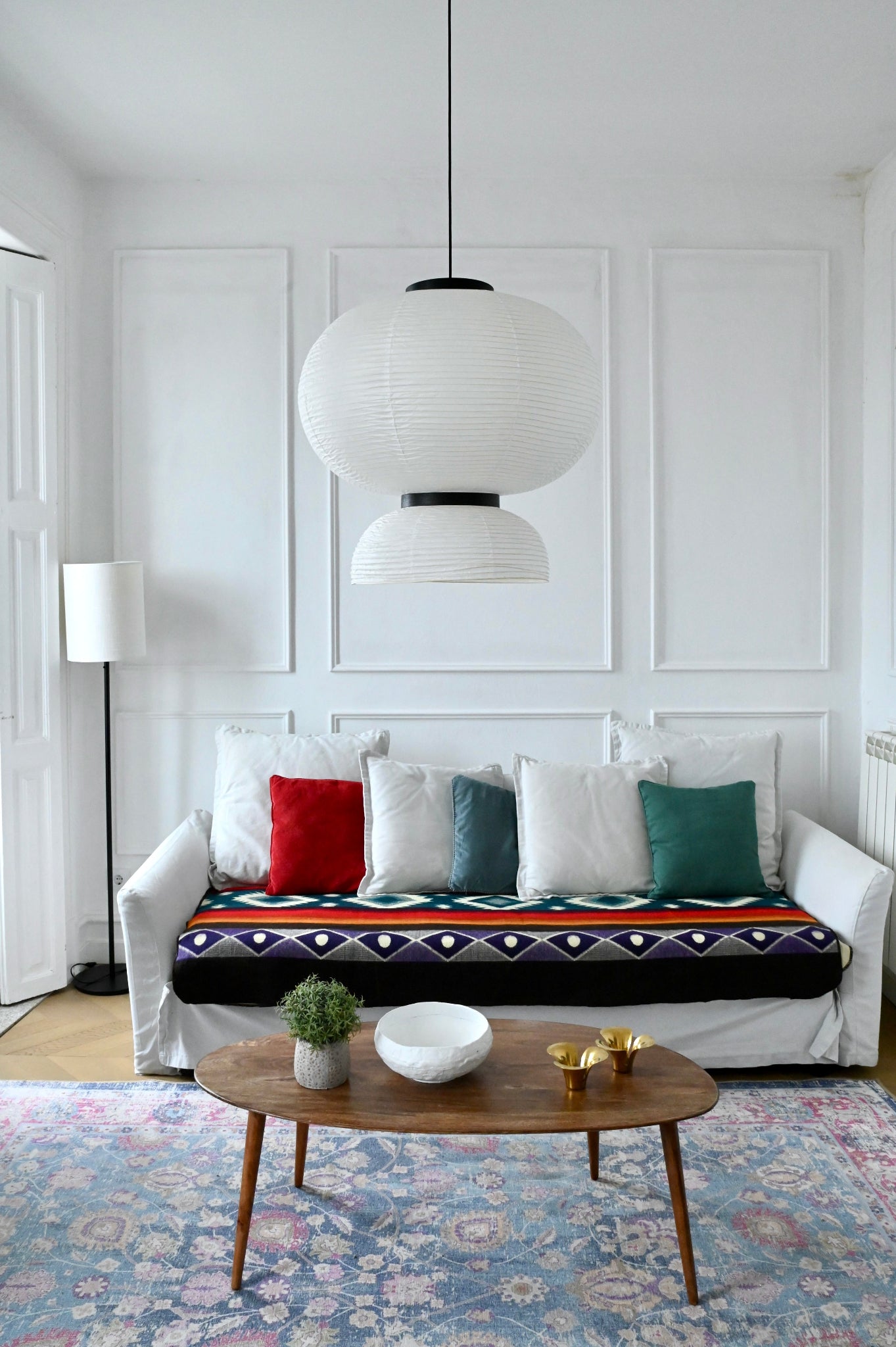 Living room with a white sofa, colorful alpaca blanket and cushions, and a wooden coffee table.