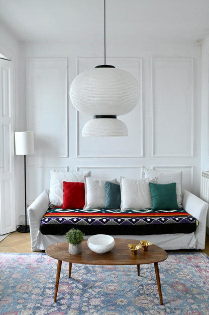 Living room with a white sofa, colorful alpaca blanket and cushions, and a wooden coffee table.