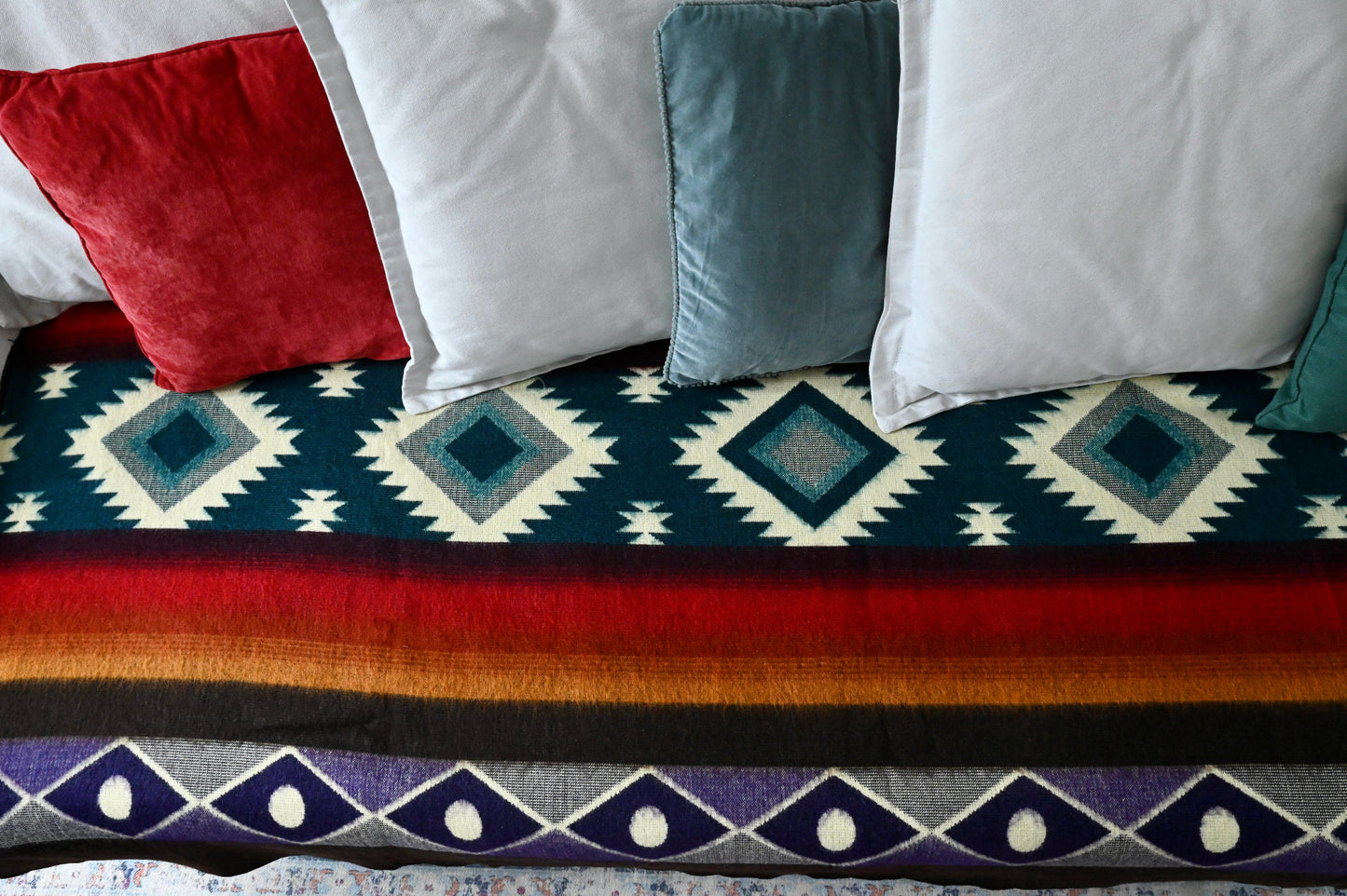 Decorative alpaca throw blanket with geometric pattern on a surface with pillows.