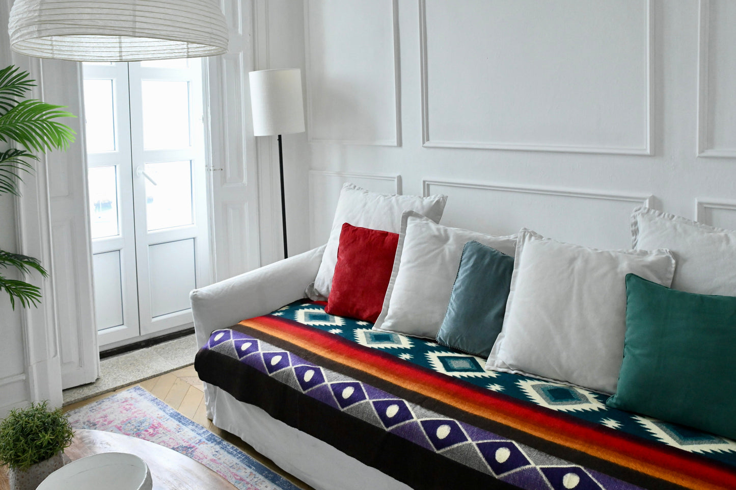 White sofa with colorful patterned alpaca throw blanket and pillows in a bright living room.