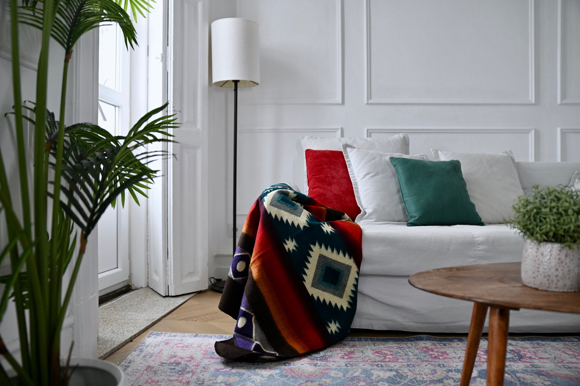 Living room with a white sofa, colorful  alpaca blanket, and decorative pillows.