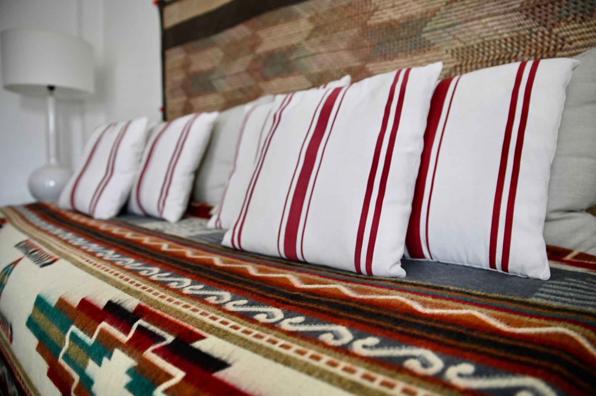 Striped pillows on a patterned alpaca blanket sofa with a lamp in the background