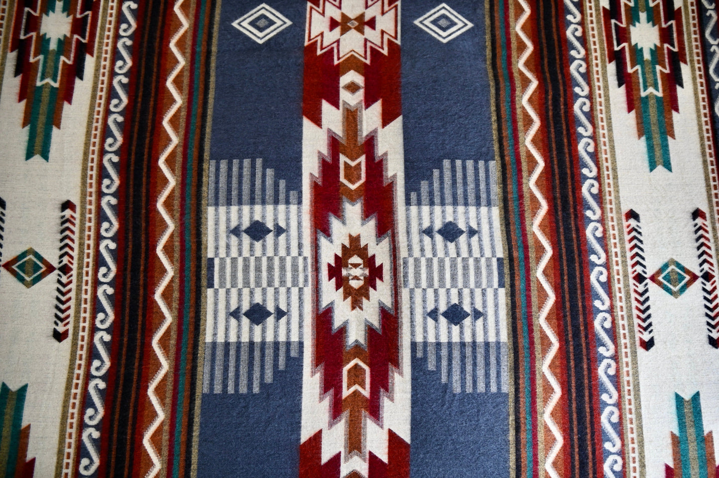 Close-up of a patterned fabric with geometric designs in red, blue, and white.
