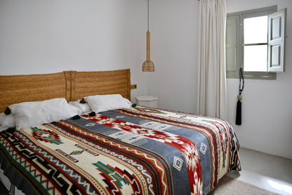 Bedroom with a bed featuring a patterned alpaca blanket and wooden headboard.
