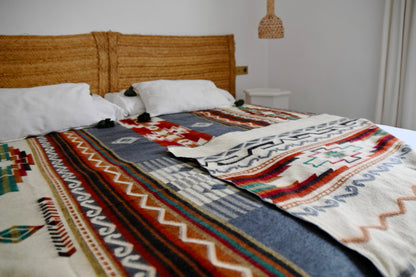 Bed with a patterned alpaca blanket and wooden headboard in a bedroom setting.