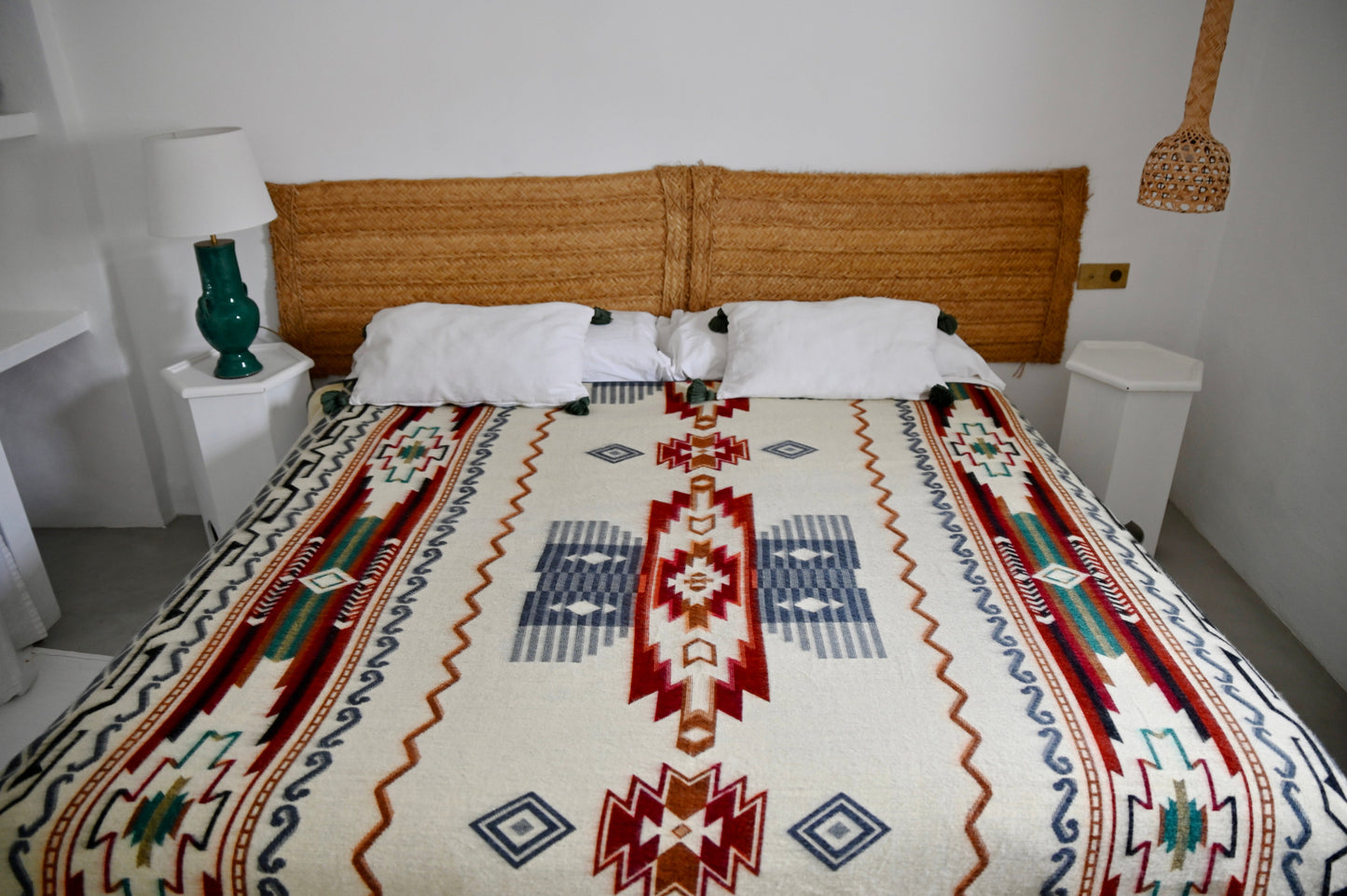 Bed with a patterned blanket in a room with a lamp and nightstands.