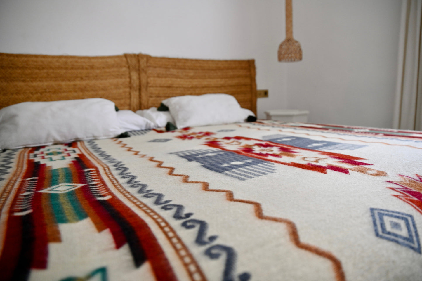 Bed with a patterned alpaca blanket in a bedroom setting