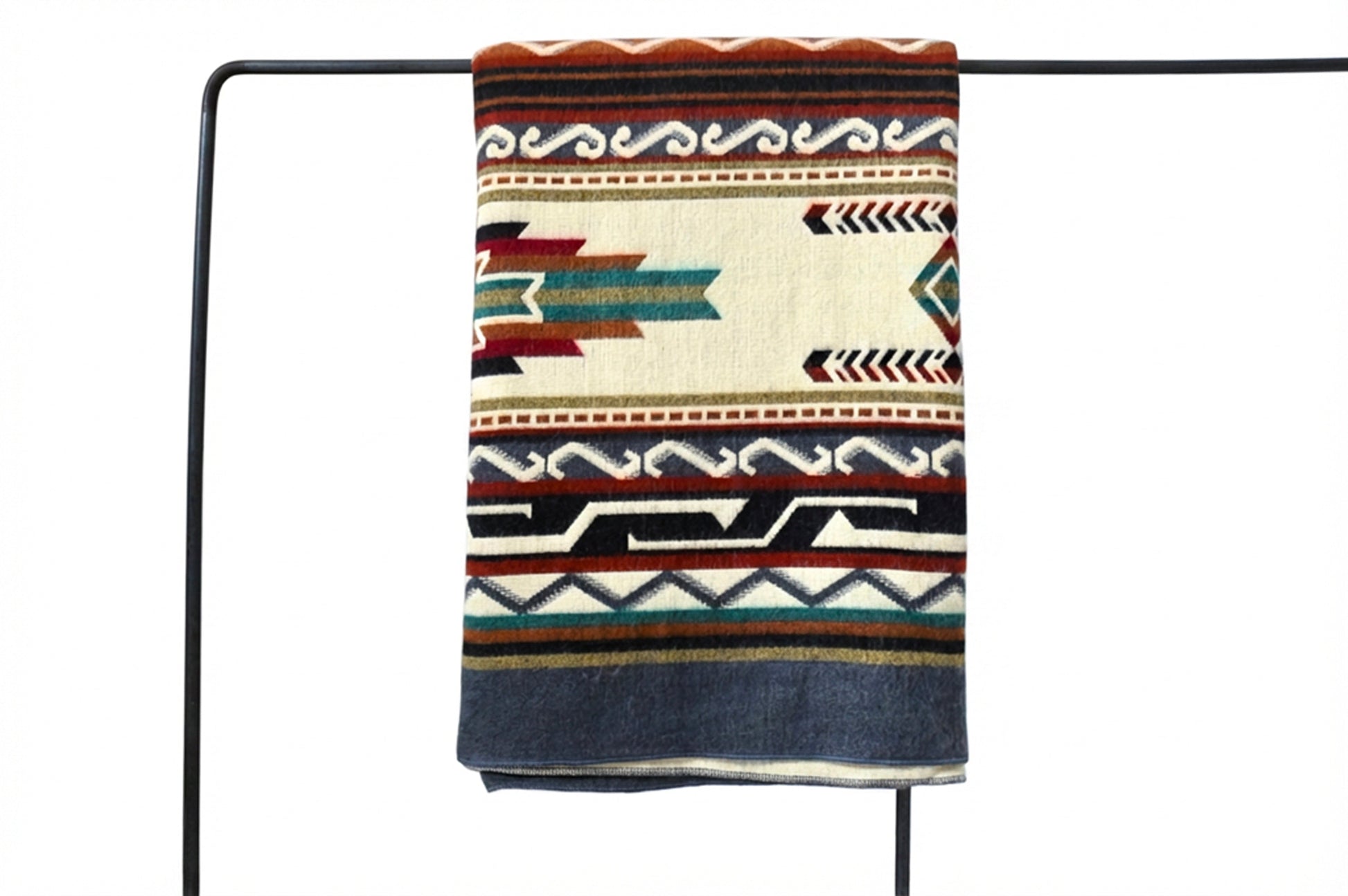 Patterned alpaca blanket draped over a black metal rod on a white background