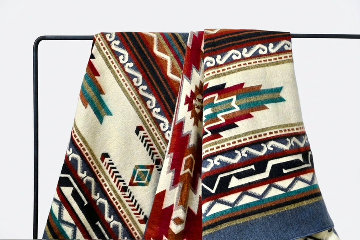 Patterned alpaca blanket with geometric design on a black metal rod