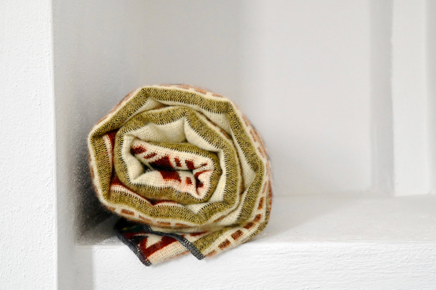 Rolled-up patterned alpaca blanket on a white background