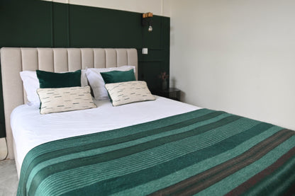 Emerald Forest striped alpaca wool blanket spread across a bed