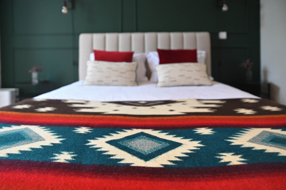 Nahaufnahme der Babyalpaka-Decke mit Aztekenmuster auf einem Bett