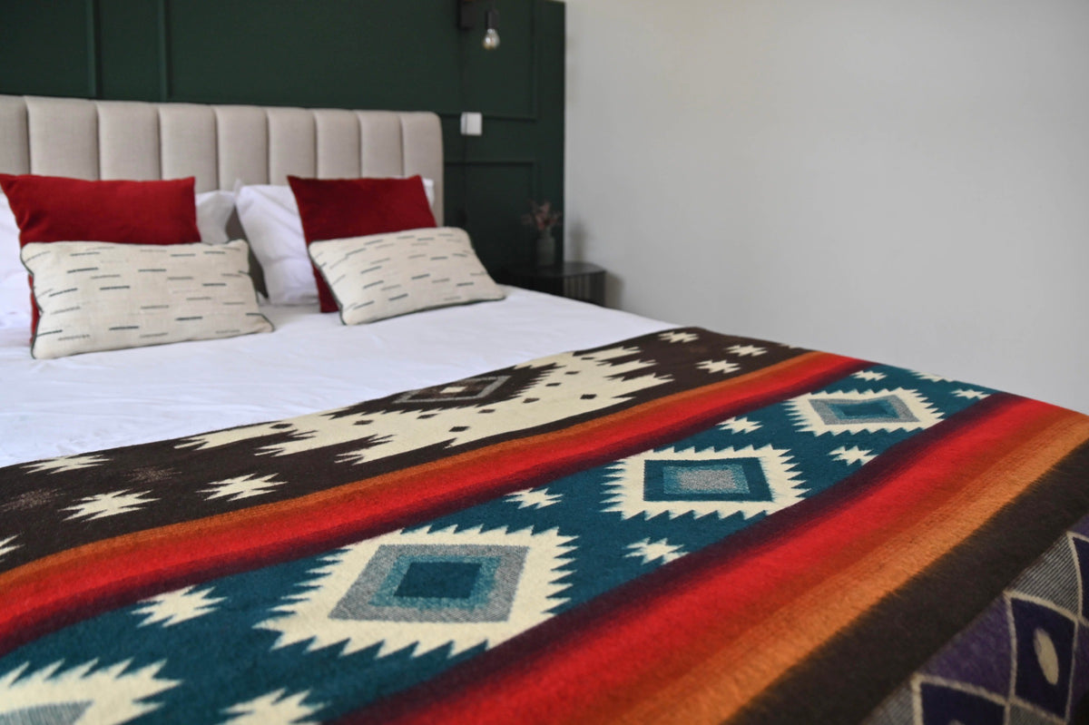 Babyalpaka-Decke mit Aztekenmuster, auf einem Bett ausgebreitet