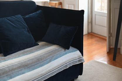 Foggy Coast striped alpaca blanket styled on a navy sofa