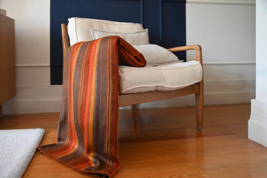 Autumn Sunset striped alpaca wool blanket draped over an armchair