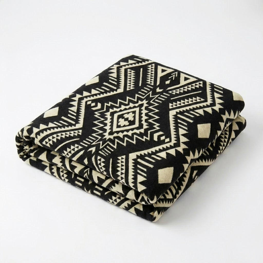 Folded black and white patterned alpaca blanket on a white background