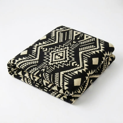 Folded black and white patterned alpaca blanket on a white background