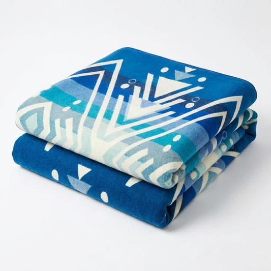 Folded blue and white patterned blanket on a white background