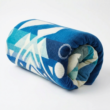 Rolled-up blue and white patterned alpaca blanket on a white background