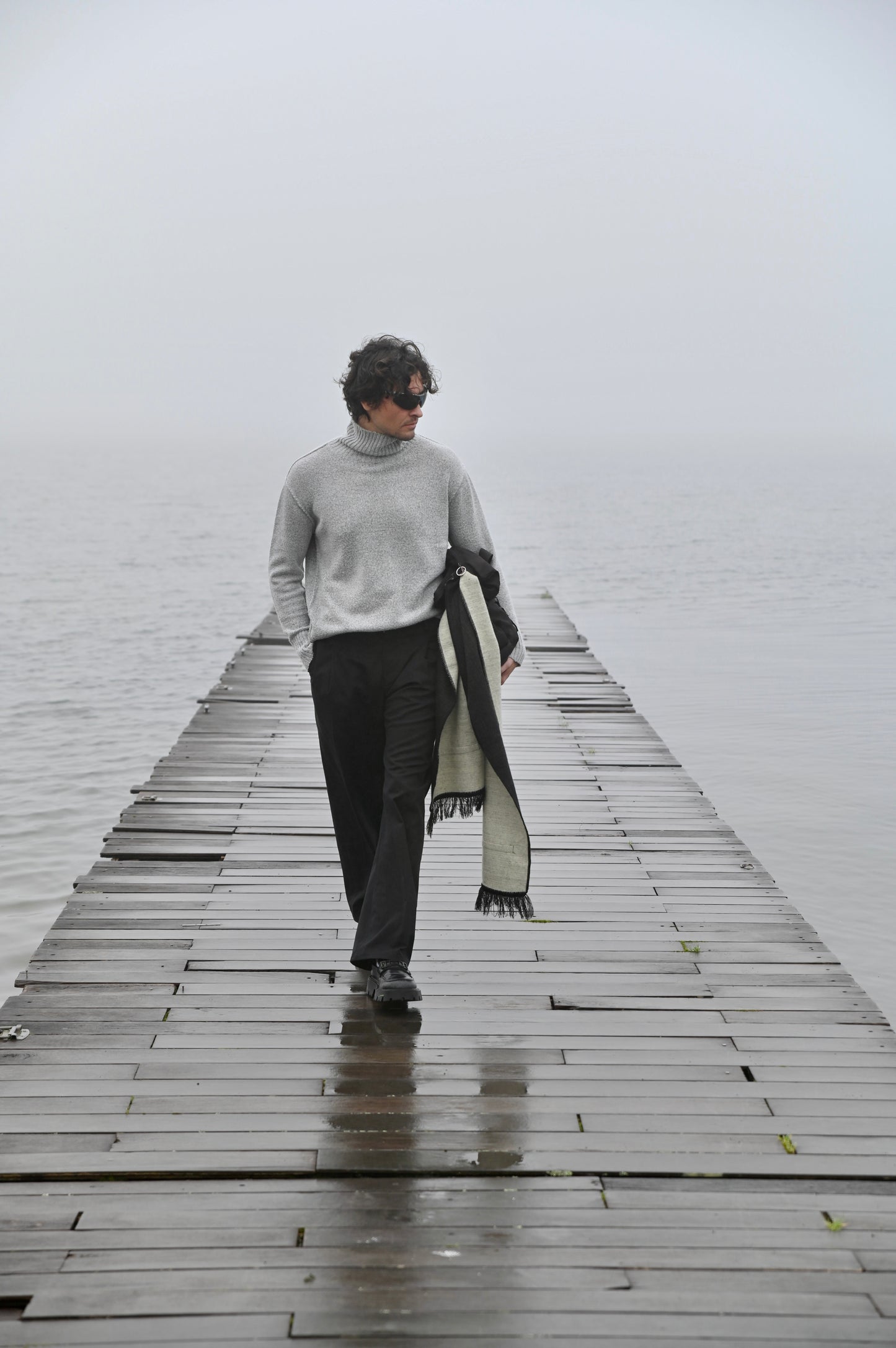 Man wearing a charcoal and ivory alpaca wool scarf outdoors by the water