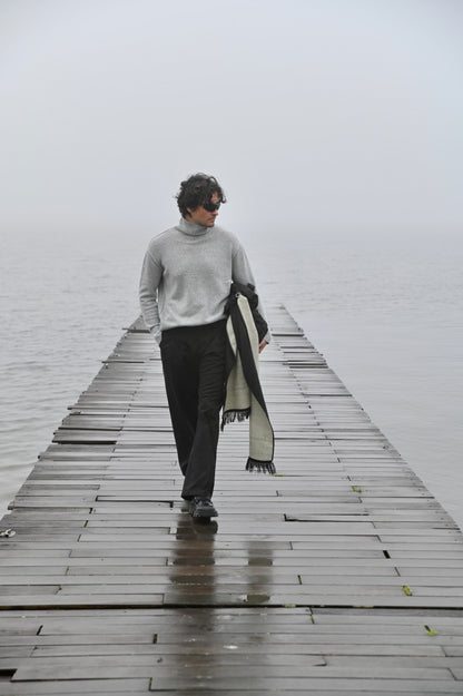 Man wearing a charcoal and ivory alpaca wool scarf outdoors by the water